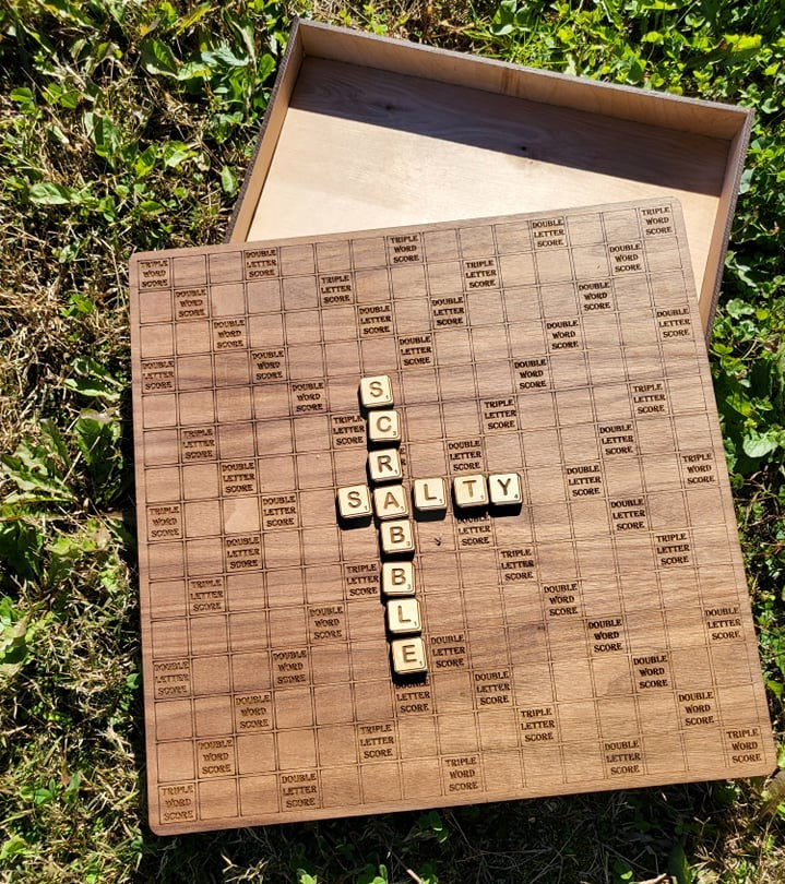 Laser cut Scrabble board game by The Hollow & Hill Co. LLC with intricately designed wooden tiles and game frame.